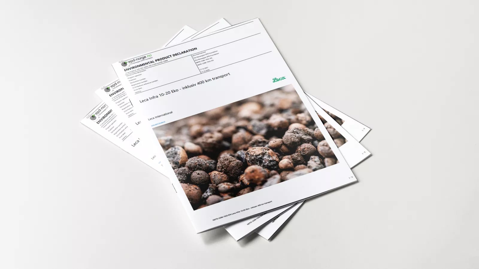 En uppsättning tryckta EPD-dokument ligger utspridda i en solfjäderform på en vit yta. Det översta dokumentet visar en närbild av Leca lättklinker och innehåller rubriker och data från miljövarudeklarationen.