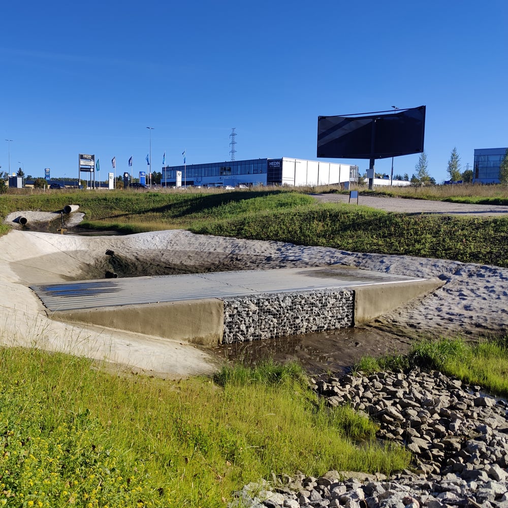 Utlopp från filterdamm med erosionsskydd och integrerad konstruktion i vägmiljö.