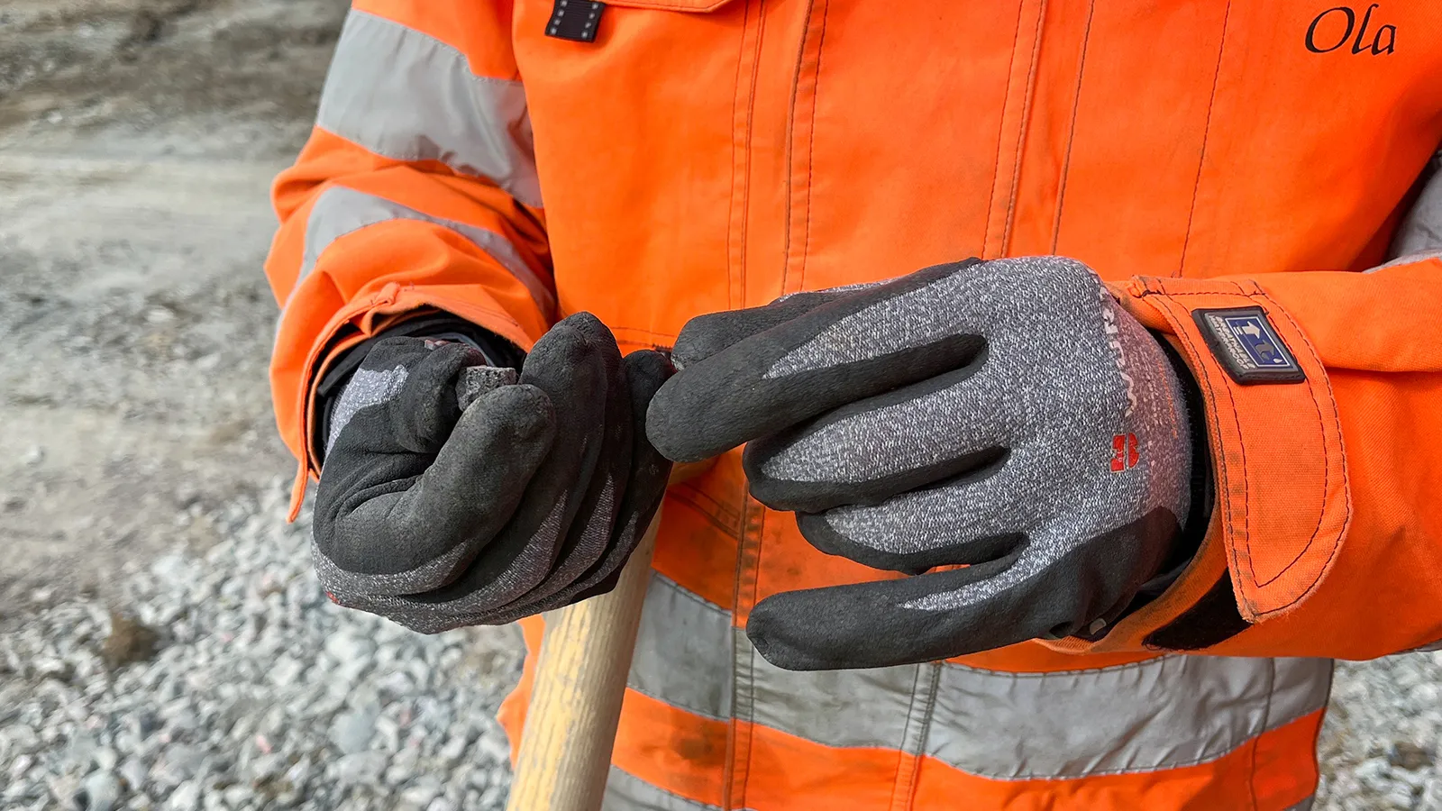 Person i varseljacka håller en lättklinkerkula i händerna med arbetshandskar på.