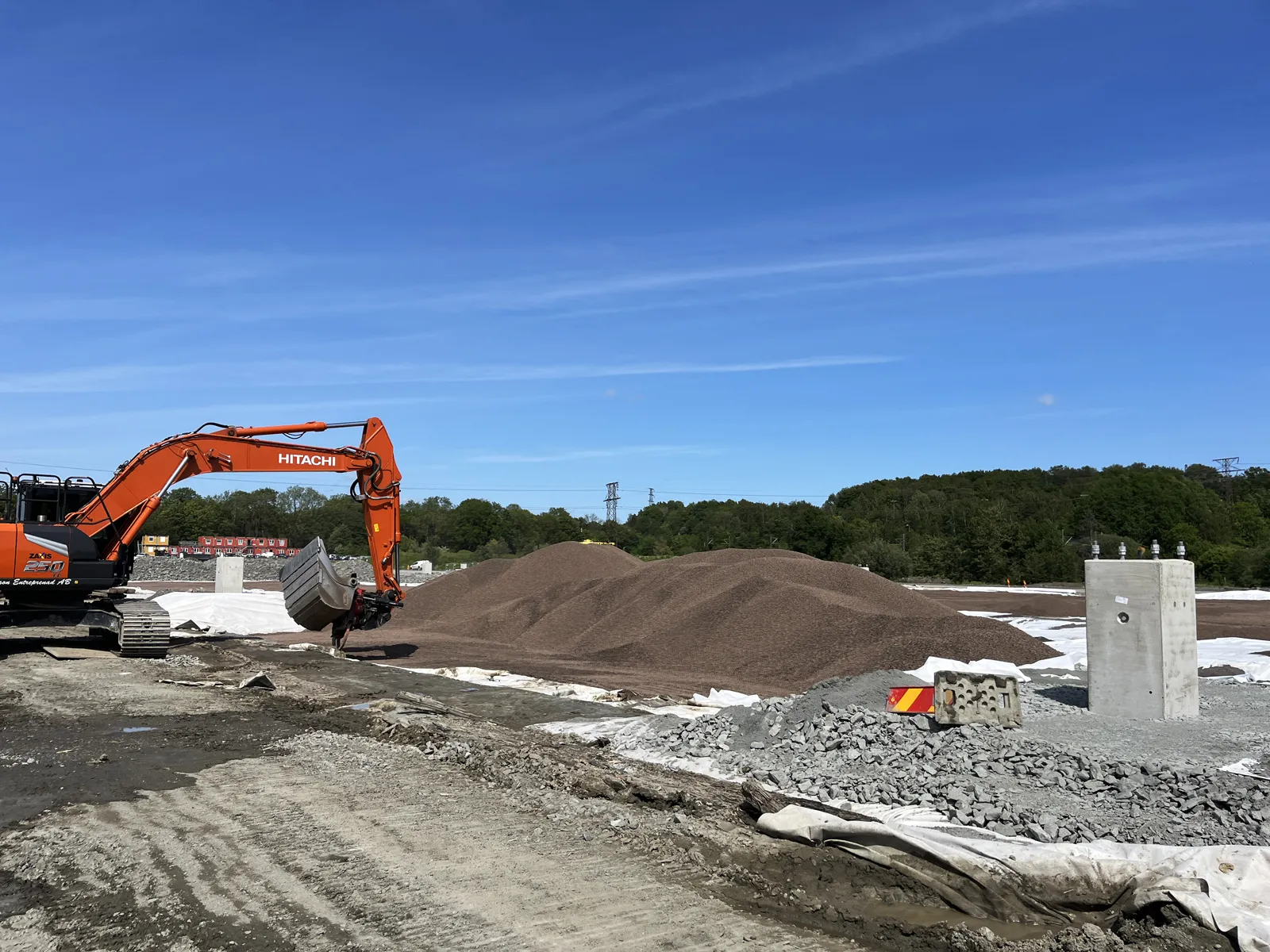 Grävmaskin vid utläggning av lättklinker på geotextil i infrastrukturprojekt