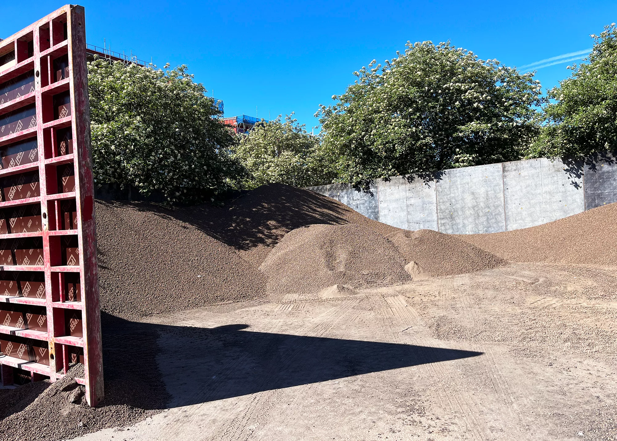 En röd vägg ramar in högar med leca lättklinker